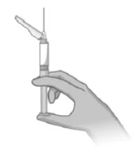 A hand holding a syringe vertically with the needle pointing upward