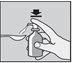 A hand presses the dispenser of a bottle to dispense a liquid dose into a spoon placed to the side