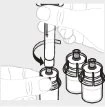 A hand rotates an injection pen over the cap of a glass vial next to two other similar vials