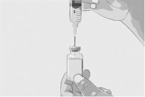 A hand holds a glass vial while