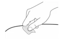 Una mano tiene e applica un cerotto adesivo su una linea curva scura che rappresenta una superficie o un tubicino