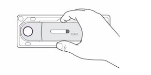 Una mano tiene un dispositivo medico rettangolare con un pulsante circolare e una fessura orizzontale con la scritta CAD