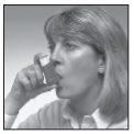 A woman with light-colored hair holding an inhaler close to her mouth, ready to use it for medication