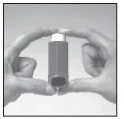Two hands holding vertically a dark cylindrical bottle with a white cap to show its appearance
