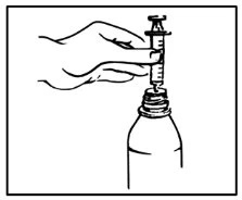 Una mano impugna una siringa con ago inserito nel collo di un flacone di vetro per aspirare il contenuto del farmaco