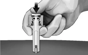 A hand pressing downward with the thumb on the top of a medical device for