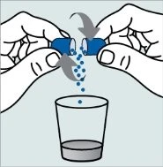 Due mani separano una capsula blu facendone cadere il contenuto granulare all'interno di un bicchiere trasparente con del liquido