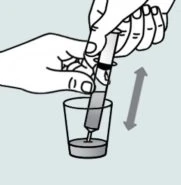 Due mani tengono una siringa e la muovono verticalmente su e giù all'interno di un bicchiere contenente del liquido