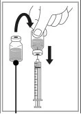 A hand tilts a glass vial to pour liquid into a syringe with needle positioned vertically beneath the container