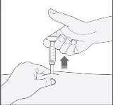 A hand holding a syringe vertically while the