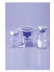 Three transparent glass vials with metal caps arranged on a reflective surface against a light blue background