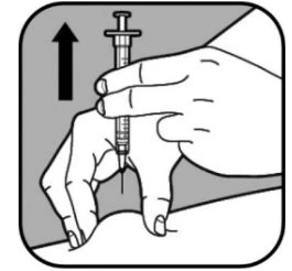 A hand holds a syringe vertically while the