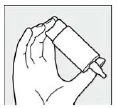 A hand holding a tilted cylindrical bottle with a dropper applied at the top edge to administer medication