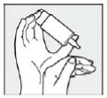 Two hands holding and tilting a medicine bottle to prepare the dosage or the