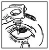 A gloved hand applying a drop of eye drops directly onto the surface of the eye