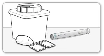 Medical waste disposal container with lid, an injection pen and two small white rectangular containers on a flat surface