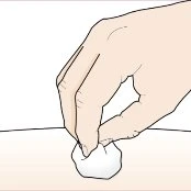 A hand gently pressing a white cotton ball onto the surface of light-colored skin