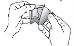 Two hands grasping and carefully separating a medicinal package or wrapper along a central tear line