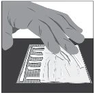 A human hand grasps and opens a white plastic pouch with serrated edges on a dark surface
