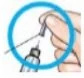 A hand holding a glass vial while a needle is inserted through a rubber stopper to draw liquid medication