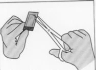 Two hands opening a rectangular pouch using a pair of scissors to remove a medical instruction leaflet