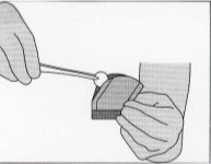 Two hands using a spatula to apply a small amount of cream onto the surface of a flat, rectangular applicator