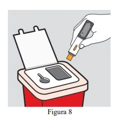 A hand holds a white and orange medical device above an open container with a compartment for a rectangular object and a small circular hole