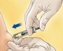 Mani guantate che tengono una siringa per iniettare un farmaco nel gluteo di un paziente con una freccia blu che indica il movimento di estrazione
