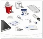 Medical devices on a table including a sharps waste container, a blood pressure monitor, vials, syringes, bandages, and dressings