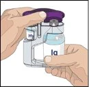 Две руки держат и нажимают на прозрачное медицинское устройство с фиолетовой крышкой для подготовки внутреннего жидкого лекарства