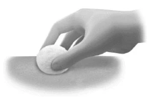 Una mano preme un dischetto di cotone bianco sulla superficie della pelle per applicare una medicazione o pulire una zona del corpo