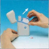 Two hands opening the lid of a white and light blue medical device placed on a light surface with a red pill beside it