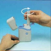 Two hands using a white medical device with open lid and a curved white arrow indicating the rotation movement of the cylinder