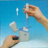 A hand lifting a white cylindrical medical device from a white plastic base on a light blue background with a white arrow pointing toward the