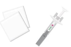 Two square white adhesive patches placed next to a grey syringe with white grip and green and pink markings on the central body