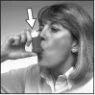 A woman with light-colored hair holds a small bottle near her mouth while a white arrow points to the container