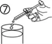 A hand holding a syringe tilted to let drops of liquid fall from the
