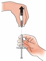 Two hands holding a syringe to draw liquid from a vial by pulling the plunger upward
