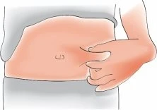 A hand grasping a fold of skin on the abdomen