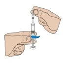 Two hands holding a vertical syringe with blue liquid inside