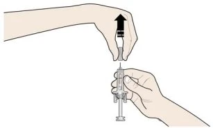 A hand grasping the top of a syringe while the
