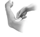 One hand applying a patch or adhesive dressing to the upper arm of a person in grayscale