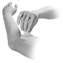 One hand holding a small patch or adhesive dressing applied to the upper arm near the elbow in black and white