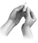 Two hands carefully holding and opening a small pouch or envelope made of translucent material to remove its contents