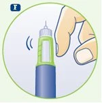 Una mano tiene un dispositivo medico cilindrico blu e verde con un ago esposto in cima su sfondo bianco circondato da un bordo verde