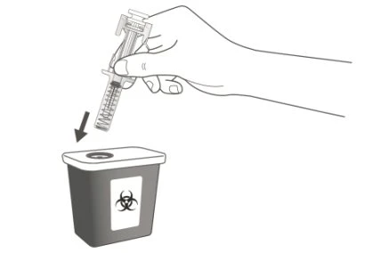 A hand holds a syringe with needle pointing downward to insert it into a biohazard waste container with biohazard symbol