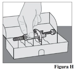 A hand holding a pre-filled syringe horizontally above an open cardboard box with internal compartments for storage