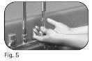 Hands holding a glass vial and a cylindrical container near a vertical metal stand against a blurred background