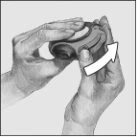 Two hands holding a circular medical device and rotating it clockwise, as indicated by a curved white arrow