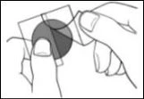 Two hands hold and separate two transparent rectangular sheets enclosing a central dark disc for application